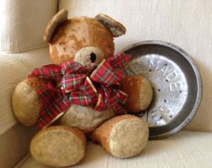 photo of worn Teddy with tartan bow and antique pie tin